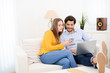 © W PRODUCTION - cheerful young couple on sofa at home websurfing and shopping online with laptop computer internet technology