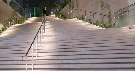 Sticker - Businesswoman looking at cellphone and walking down the step