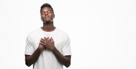 Poster - Young african american man wearing white t-shirt smiling with hands on chest with closed eyes and grateful gesture on face. Health concept.