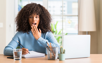 Poster - African american woman studying at home using a computer laptop cover mouth with hand shocked with shame for mistake, expression of fear, scared in silence, secret concept