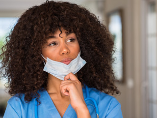 Poster - African american woman medical professional serious face thinking about question, very confused idea