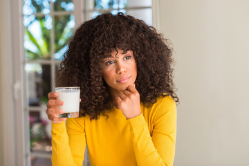 Sticker - African american woman holding a glass of milk serious face thinking about question, very confused idea