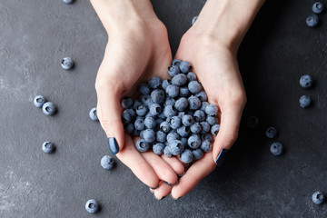 Wall Mural - Close up of woman hands holding fresh blueberries. Healthy eating, dieting and vegetarian food concept.