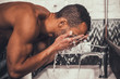 © VadimGuzhva - Young Afro-American Man Washing Face in Bathroom.