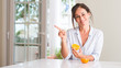© Krakenimages.com - Middle aged woman holding orange fruit very happy pointing with hand and finger to the side