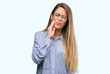 © Krakenimages.com - Beautiful young woman wearing elegant shirt and glasses touching mouth with hand with painful expression because of toothache or dental illness on teeth. Dentist concept.