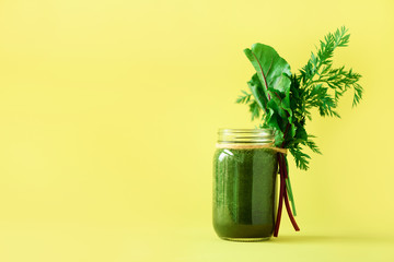 Wall Mural - Fresh smoothie with beet greens and carrot tops on yellow background, copy space. Summer vegan food concept. Healthy detox diet. Fresh squeezed juice, drink from vegetables. Leafy greens.