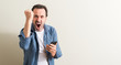Senior man using smartphone annoyed and frustrated shouting with anger, crazy and yelling with raised hand, anger concept