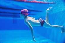 A Little Boy Is Having Fun Under Water, Tumbling And Grimacing, Making Faces