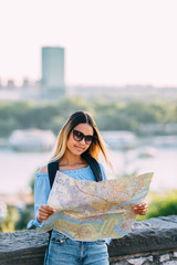 Wall Mural - Young female traveler lost in city looking at the map 