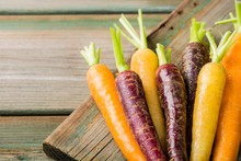 Fresh Raw Colorful Carrots Roots, Purple, Yellow And Orange On Old Wooden Table. Healthy Food Vegetable Background With Copy Space.