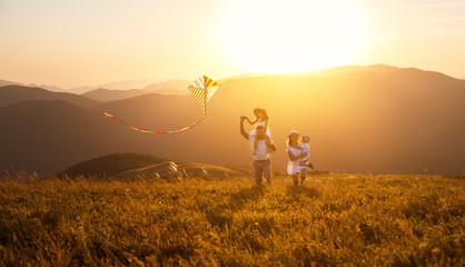 Wall Mural - Happy family father,  mother and children launch  kite on nature at sunset