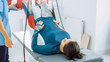 Physiotherapist Assists Female Patient with Trauma, Undergoing Rehabilitative Physiotherapy on a Special Suspension Rope System. Relieving Back Pain. Modern Clinic Using Rehabilitating Procedures.