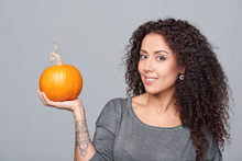 Smiling Curly Woman Holding Ripe Pumpkin Isolated Over Grey Background