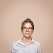 Girl in glasses looks up at copyspace. Beige background.