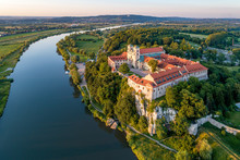 Tyniec Near Krakow, Poland. Benedictine Abbey, Monastery And Church On The Rocky Cliff And Vistula River. Aerial View At Sunset. Bielany Monastery Far In The Background