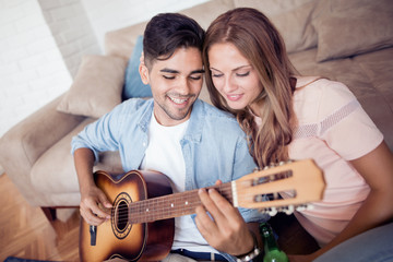 Poster - Lovely young couple playing guitar at home