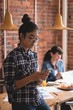 © Wavebreak Media - Young businesswoman using smartphone while standing in office