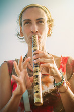 Young Woman Playing Bamboo Flute On Summer Day