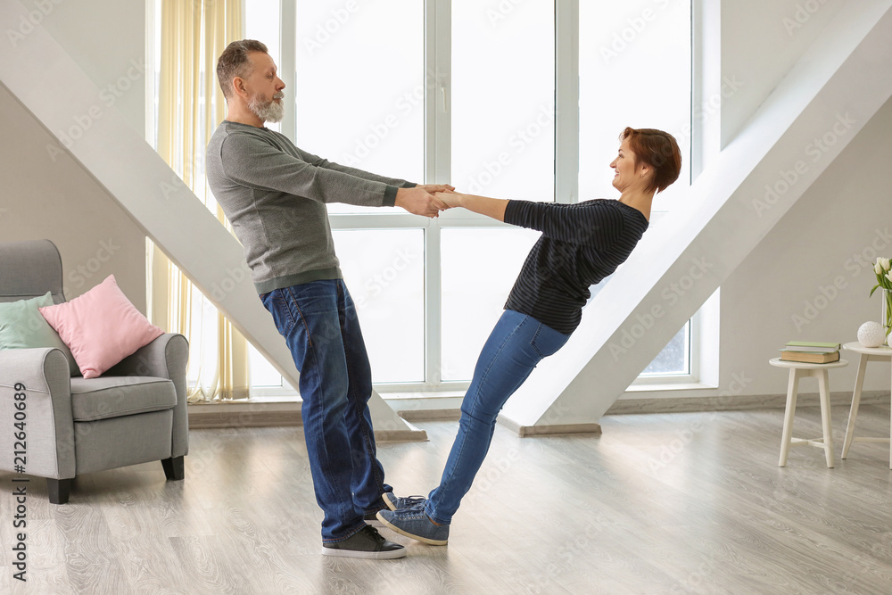 Happy mature couple dancing at home