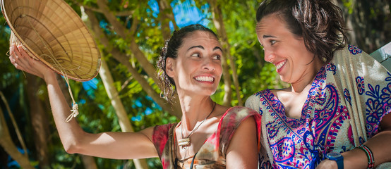 Wall Mural - Two happy girlfriends smiling and enjoying on the beach