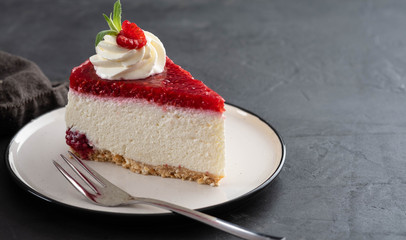 Cheesecake slice with fresh raspberries and mint leaves on a white plate. Copy space.