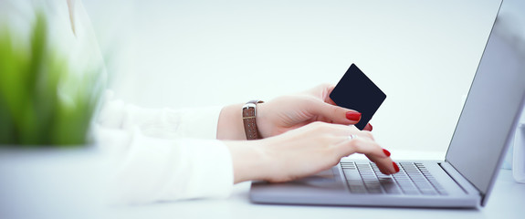 Close-up of woman's hands holding a credit card at a computer keyboard. Convenient set of funds budget wallet deposit wealth and effective investment invest resources income profit concept