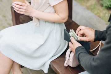 Wall Mural - cropped view of man pickpocketing money from wallet of woman in park