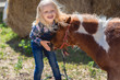© LIGHTFIELD STUDIOS - adorable smiling kid touching cute pony at farm