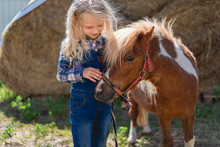 Happy Kid Palming Cute Pony At Farm