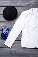 Wall Mural - Vertical image glamour women's clothing. White jacket, blue wallet and black hat, top view.