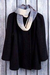 Wall Mural - Black wool cardigan and scarf. Wooden desk background.