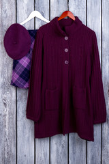 Wall Mural - Wool purple coat, flat lay. Top view. Dark wooden desk surface background.