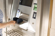 © Marina - A woman uses a credit card at an ATM on the street. Operation with money. Payment. Copy space.
