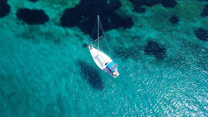 Aerial drone birds eye view of sail boat docked in an Ionian island with crystal clear emerald sea, Greece