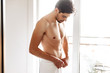 © Drobot Dean - Naked man standing indoors at bathroom with towel