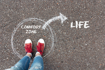 Wall Mural - Exit from the comfort zone concept. Feet  standing inside circle comfort zone and outward arrow chalky on the asphalt.