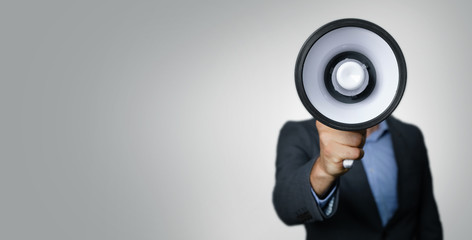 announcement - businessman with megaphone in front of face on gray background