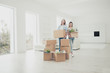  Dream of all our life! Buyer mover owner belongings concept. Two charming cheerful with toothy smile people holding carrying packages with thinks in hands standing in spacious light white living room