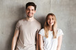 © Drobot Dean - Portrait of young smiling people guy and girl 20s in basic clothing posing together at camera with happy look, isolated over concrete gray wall indoor