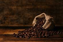 Bunch Of Fresh Roasted Coffee Beans With Burlap Sack On A Wooden Table. Agriculture And Drink Concept