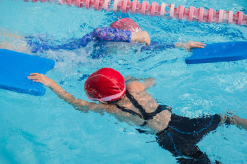 two girls learn how to swim in swimming class