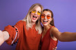 © ClaudiK - Studio lifestyle portrait of two best friends hipster girls wearing stylish bright orange outfits, dresses and sweater,sunglasses.Two beautiful young women in casual clothes in studio.
