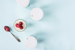 Open jar with homemade yogurt and raspberries next to closed jars on a blue background. Top view, flat lay, copy space