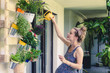 © Alexander - beautiful pregnant young woman watering plants on her balcony