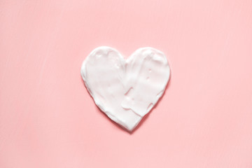 heart shape from cream in pink background. skin care.