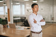 © mavoimages - Focused Asian businessman standing in an office deep in thought