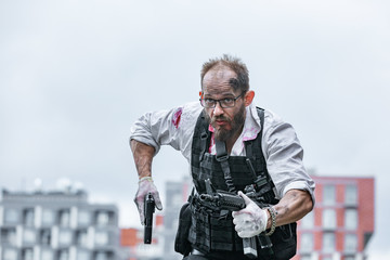 man dressed in a bulletproof vest, a shirt in his blood, pursues a victim with a gun Action Movie Style