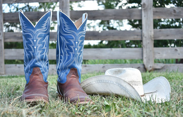 cowboy boots and hat with a farm gate