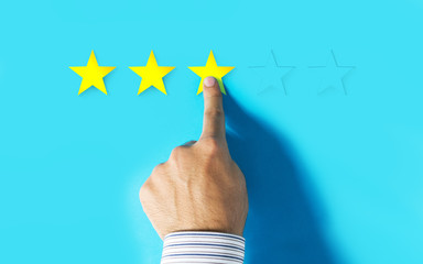 Hand choosing three stars rating on blue background